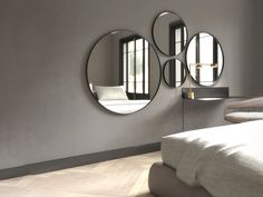 three circular mirrors mounted on the wall above a bed