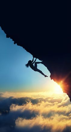 a person climbing up the side of a mountain with clouds in the foreground and sun behind them