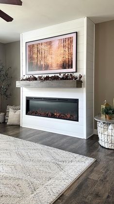 a living room with a white fireplace and large rugs on the hardwood flooring