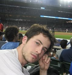 a man sitting in the stands at a baseball game with his hand on his face