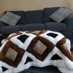 a living room with a blue couch and brown and white fur rug on the floor