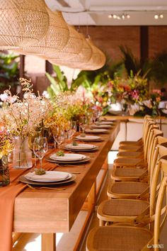 a long wooden table topped with plates and vases filled with flowers