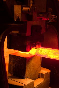 a piece of metal that is melting in some kind of furnace with red light coming from it