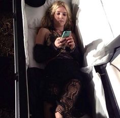 a woman laying in bed looking at her cell phone