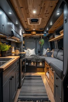 the interior of a camper with wood paneling and gray cabinets, grey rugs and wooden flooring