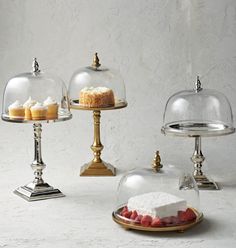 three cakes under glass domes on gold platters