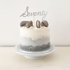 a cake with frosting and two candles on it sitting on a white plate that says seventy