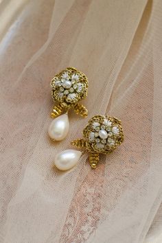 These vintage-inspired wedding earrings bloom with intricate handcrafted lace blossoms. The flower petals are enhanced with ivory silk embroidery, while clusters of vintage crystals sparkle at their centers. A freshwater pearl teardrop hangs from a sprig of hand-beaded leaves, making the a romantic addition to your bridal look. ⁠ ⁠ Handcrafted in our Vermont, USA, studio using old-world lacemaking techniques and heirloom-quality materials. Shop the collection online at ederajewelry.com⁠ Flower Shaped Clip-on Wedding Jewelry, White Pearl Drop Bridal Earrings For Reception, Traditional Handmade Flower Jewelry For Wedding, Traditional Wedding Jewelry With Handmade Flowers, Handmade Flower Shaped Pearl Wedding Earrings, Handmade Flower Shaped Pearl Earrings For Wedding, Handmade Flower Pearl Earrings For Wedding, Wedding Pearl Drop Earrings In Flower Shape, Elegant Bridal Earrings With Flower Decoration