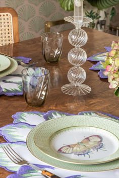 the table is set with plates, glasses, and vases on top of it