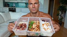 a man holding three plastic containers with food in it's hands and looking at the camera