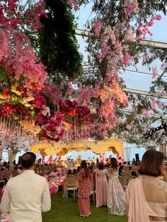 people are standing under pink flowers hanging from the ceiling