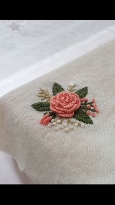 a close up of a table cloth with embroidered flowers and leaves on the edge,