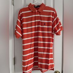 an orange and white striped polo shirt hanging on a door