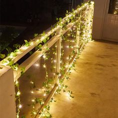 a balcony with lights and plants growing on the railing, all lit up at night