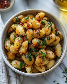 a white bowl filled with pasta and garnished with parsley on the side