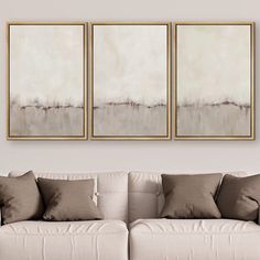 three paintings hang on the wall above a couch in a room with white furniture and pillows