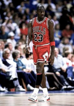 a basketball player is walking on the court with an audience in the stands behind him