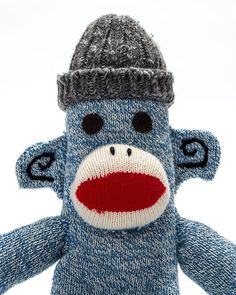 a sock monkey with a knitted hat on it's head is posed in front of a white background