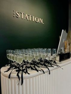 there are many wine glasses lined up on the counter top with black ribbons around them