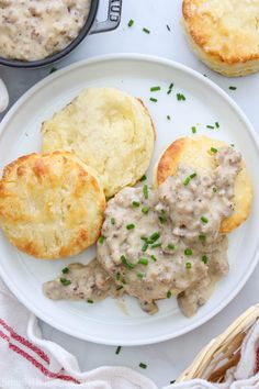 biscuits and gravy on a white plate next to bread