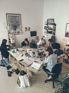 a group of people sitting around a table with papers and books on it in an office