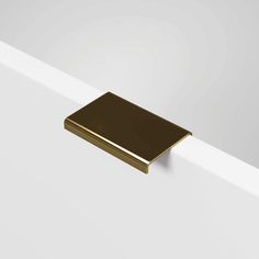 a close up of a gold square object on a white surface in an empty room