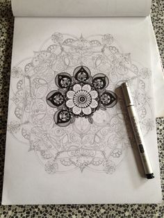 a pen sitting on top of a piece of paper next to an intricate design in black and white