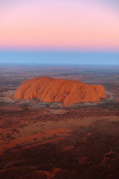 an aerial view of the aye rock formation in australia at sunset or sunrise, with pink and blue hues