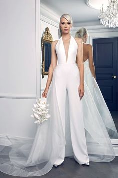 a woman standing in front of a mirror wearing a white jumpsuit