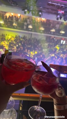 two people holding up wine glasses in front of a large audience at a concert venue