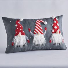 three gnomes on a gray pillow with red and white decorations