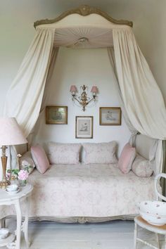 a white bed sitting under a canopy in a bedroom