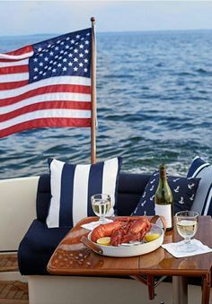 a plate of lobsters and wine on a table with an american flag