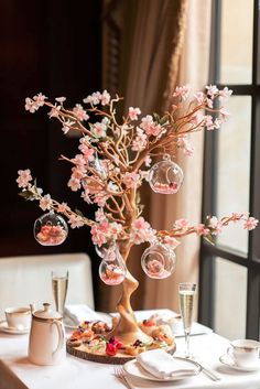 the table is set with plates, cups and flowers in vases on top of it