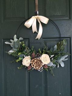 a wreath with flowers and pine cones hanging on a door