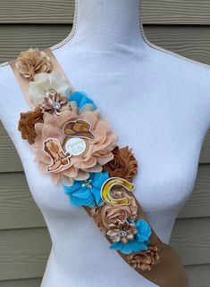 a white mannequin wearing a brown and blue flowered sash