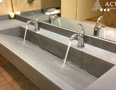 two sinks with faucets are in the middle of a bathroom counter top that is made out of concrete