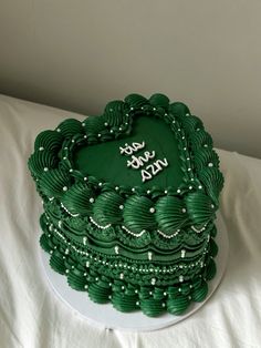 a green cake with white frosting and beads on it sitting on a table top