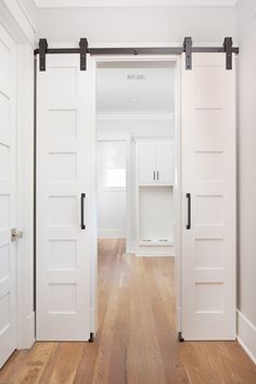 an empty room with white doors and wooden floors