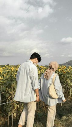 two people standing in front of a field of sunflowers