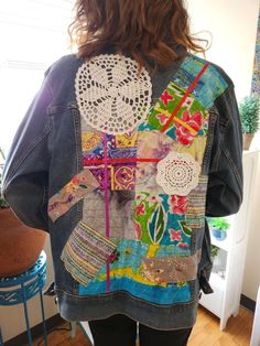 a woman standing in front of a mirror wearing a jean jacket with crochet