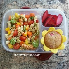 a plastic container filled with pasta salad and veggies next to a muffin