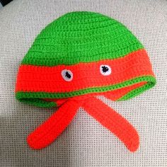 an orange and green crocheted hat on top of a white chair with eyes