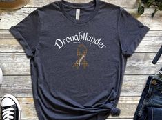 Droughtlander Survivor Short- Sleeve T-Shirt; Waiting for Outlander; Claire Jaime Fraser's Ridge, Time-travel; Outlander Book Series Well, on August 12, 2023 we enter Droughtlander AGAIN!  While I imagine it's going to be AWESOME when it returns,  I'm very anxious to get there!  Amiright?! If you too are in Droughtlander this short sleeved shirt tells your tale!  Droughtlander in Celtic script, a Fraser Tartan Cause Ribbon with Survivor on it. Sizing is in the photos.  Check out my listings as I Fraser Tartan, Outlander Claire, Jaime Fraser, Outlander Book Series, Outlander Book, Long Sleeved Shirt, August 12, Book Series, Outlander