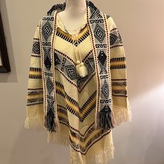 Made In Ecuador- This Beautiful Poncho Is Nwot - No Size Label - Medium 100% Wool Tassel Tie At Neck And 4” Wide Attached Scarf Tassel Trim Hem All Around Cream Background With Black Yellow Brown Orange Pattern Woven Throughout Fun Addition To Your Wardrobe - Keeps You Warm And Finishes Off Your Outfit! Length 38.5” To Longest Point Including Tassels Bin 2 Traditional Long Sleeve Poncho, One Size, Traditional Long Sleeve Poncho One Size, Traditional White Poncho For Fall, Traditional One-size Long Sleeve Cape, Traditional Long Sleeve Cape One Size, One Size Traditional Long Sleeve Cape, Beige Long Sleeve Bohemian Cape, Cream Bohemian Shawl For Fall, Cream Bohemian Poncho For Fall