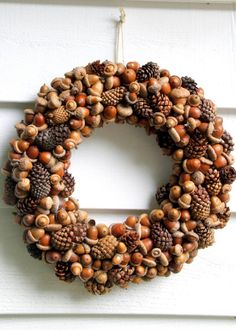 a wreath made out of pine cones and acorns is hanging on the door