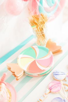 a table topped with plates and desserts on top of a striped table cloth covered in candy