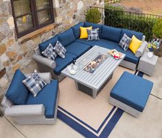 an outdoor living room with blue and yellow furniture on the outside patio, next to a stone wall