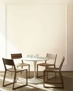 three chairs around a round table in the middle of a room with white walls and flooring