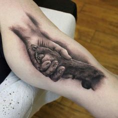 a black and white photo of a hand holding a baby's foot tattoo on the right arm